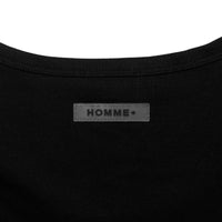 Close-up of a black garment with 'HOMME+' label on a white background